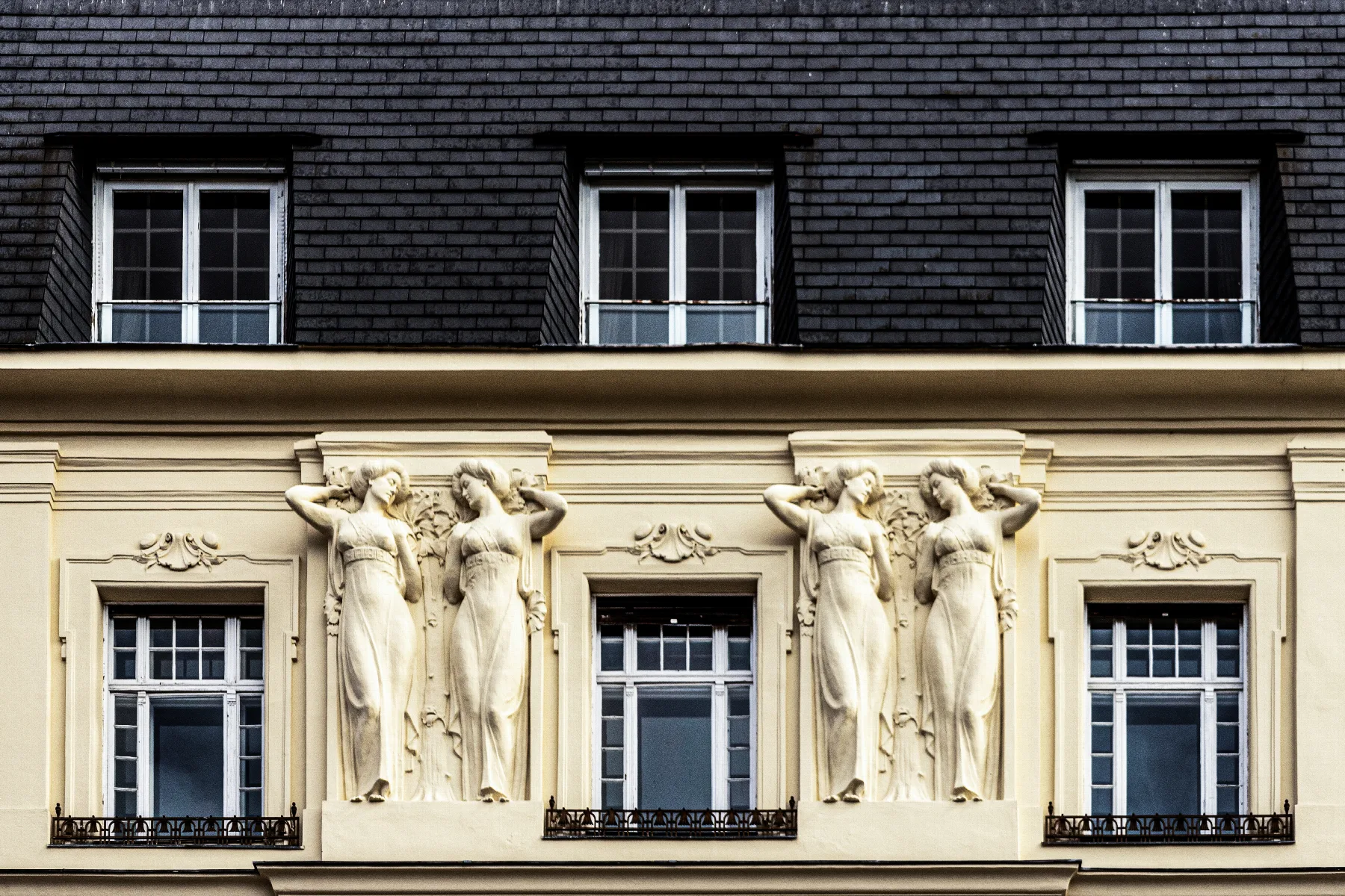 A row of carved caryatid figures supporting the facade of a Vienna residential building